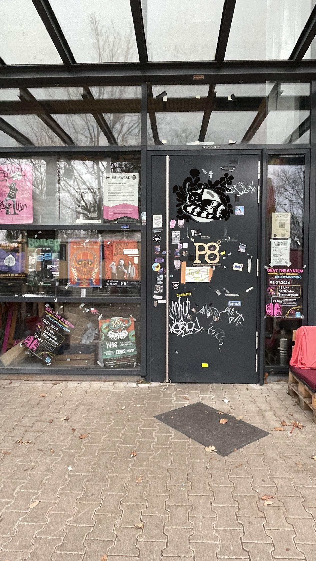 Die Tür des Kulturzentrums P8 in der Schauenburgstraße. Es zeigt verschiedene Graffitis. Unter anderem eine zwinkernde schwarzweiße Katze.