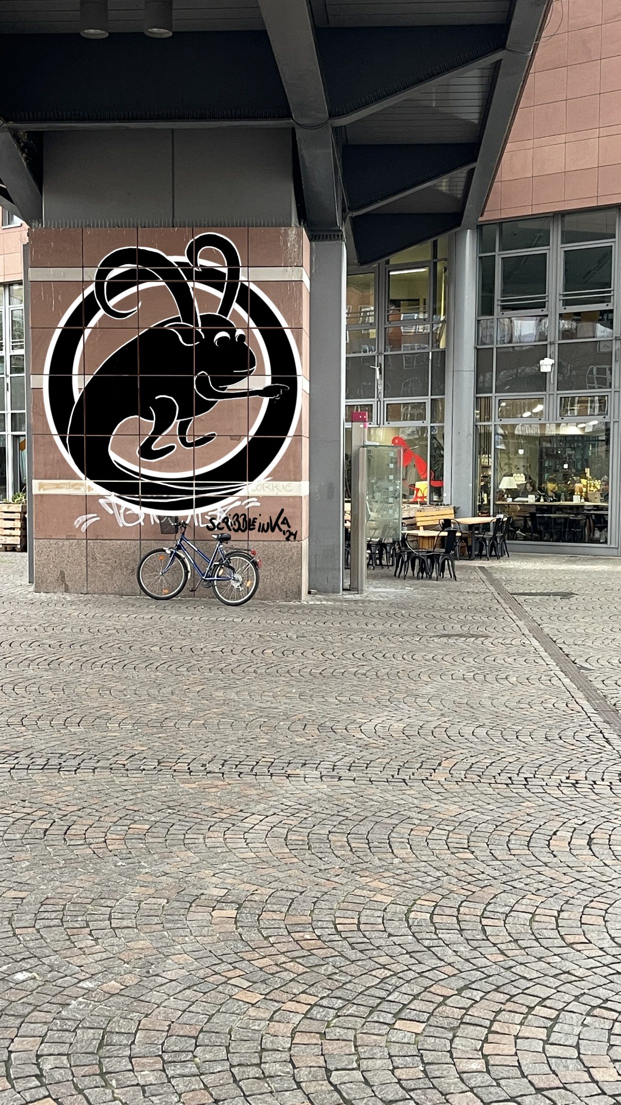 Außenwand vor dem INTRO-Cafe am Kronenplatz in Karlsruhe. Zu sehen ist ein Fabelwesen in einem Krreiis