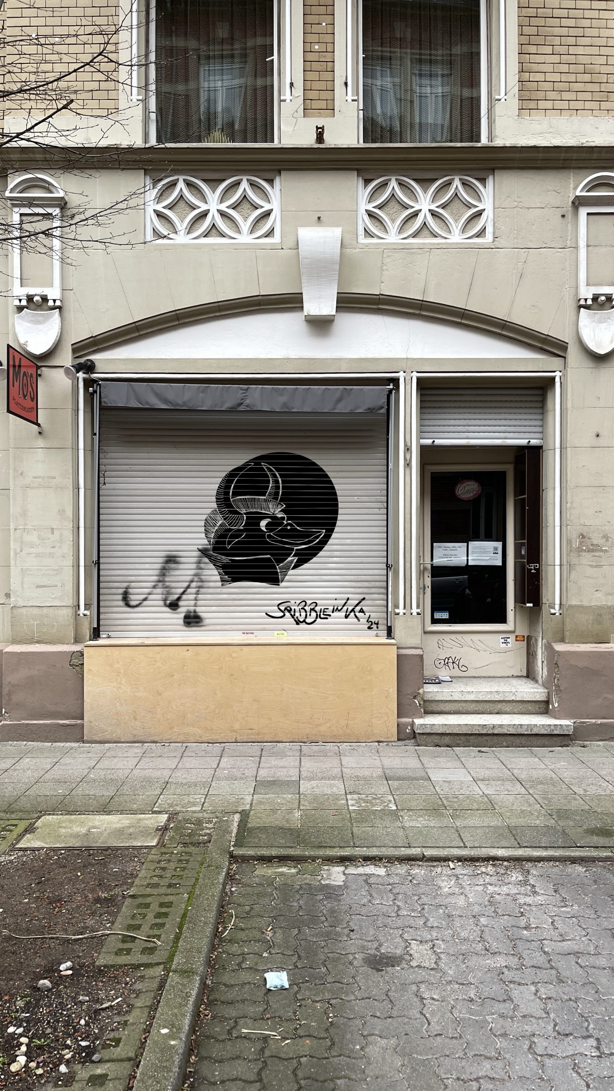 Außenseite von Mo's Plattenladen in der Rudolfstraße 17 in der Karlsruher Oststadt. Hier sieht man auf dem Rolladen ein Graffiti eines Stiers mit Irokesenschnitt und Entenschnabel