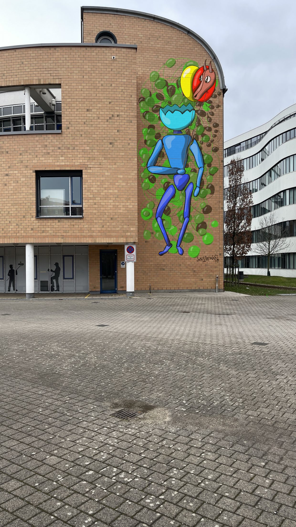 Arbeitsagentur Karlsruhe. Die Außenwand der Arbeitsagentur zeigt ein Gemälde. Bild zeigt einen Roboter mit Luftballons.