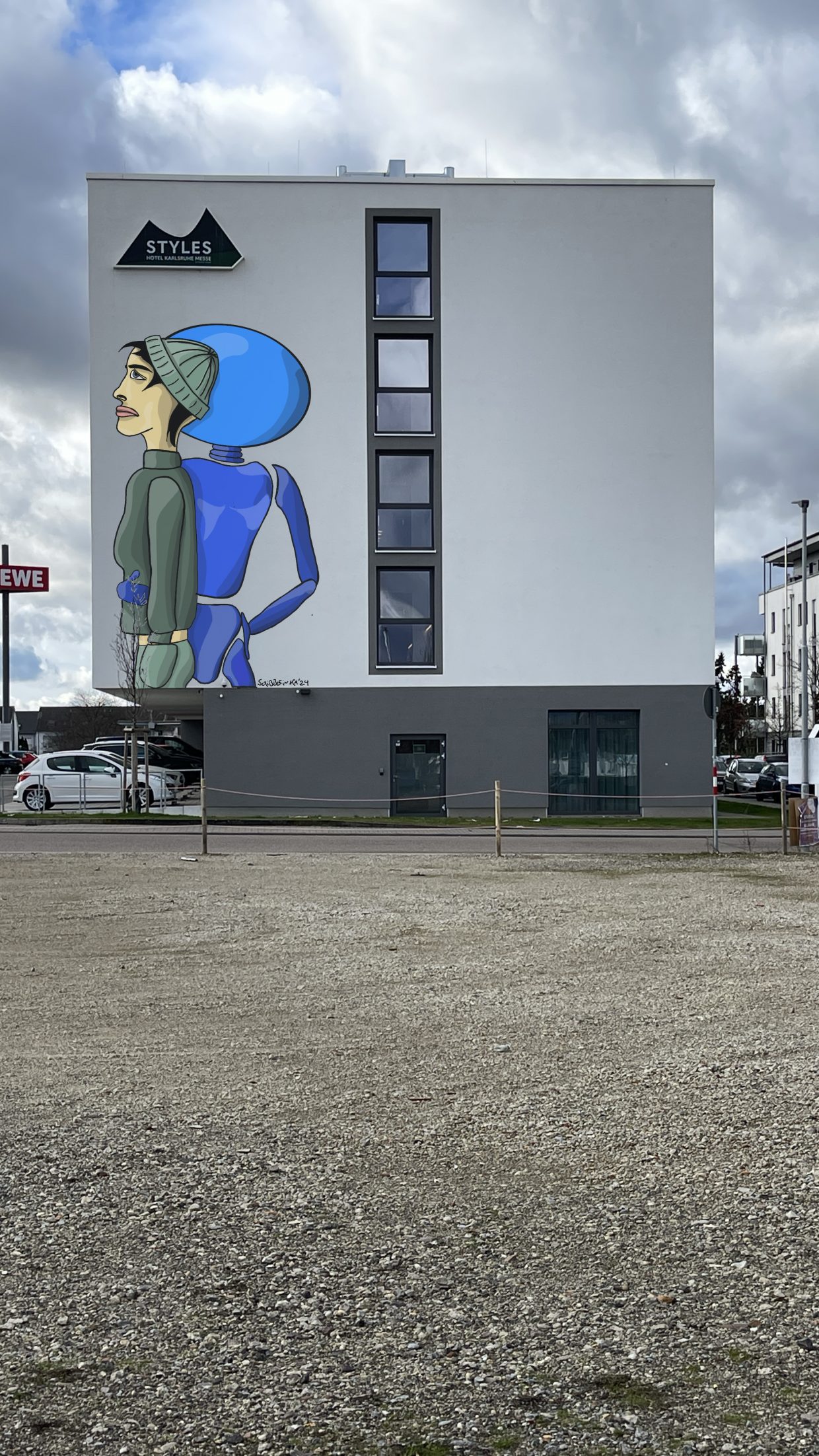 Styles Hotel in Karlsruhe, an der Karlsruher Messe (dm-Arena). An der Außenwand ein Gemälde, das eine Frau und einen Roboter zeigt.