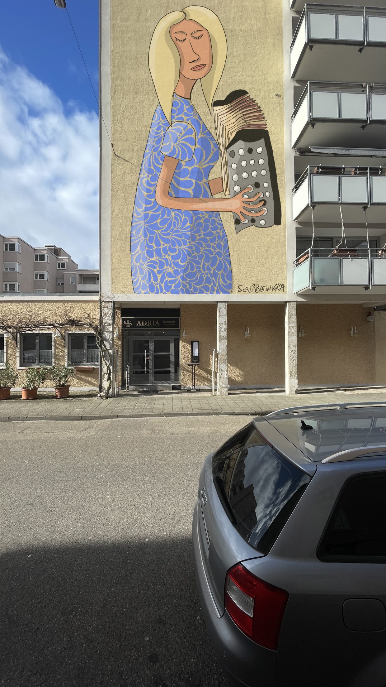 Pizzeria Adria in Karlsruhe. Die Außenwand zeigt ein Gemälde mit einer blonden Akkordeonspielerin