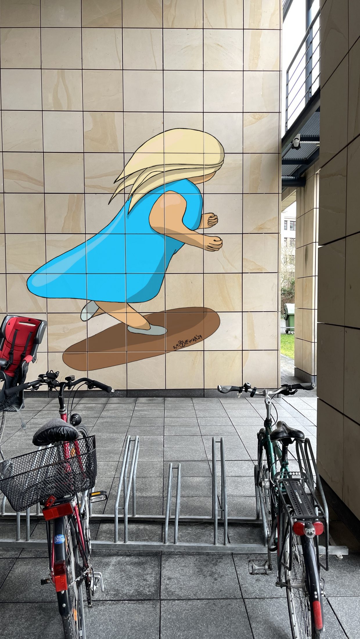 Max-Rubner-Institut in Karlsruhe, Wand mit Fahrradständer. Auf der Wand ein Gemälde mit einer Frau auf einem Skateboard.