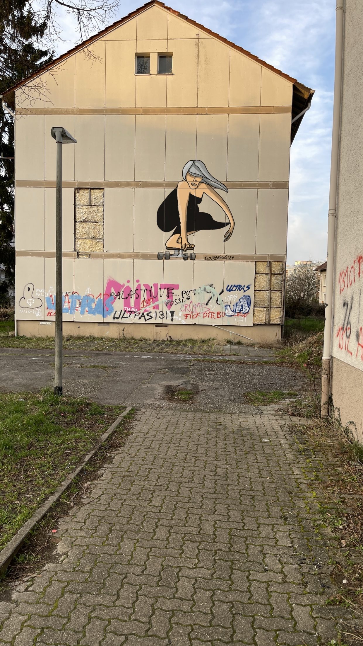 Abbruchreifes Haus in der Karlsruhe Oststadt. Verschieden besprüht. Unter anderem mit dem Bild einer grauhaarigen Frau auf einem Skateboard.